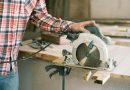 A carpenter in a plaid shirt uses a circular saw in a workshop, showcasing craftsmanship.