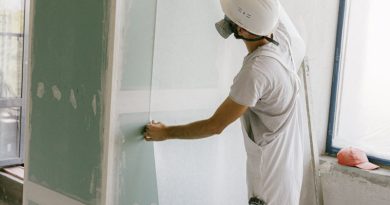 Construction worker in hard hat applying wallpaper inside a building under renovation.