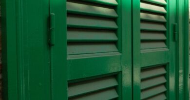 Green louvered shutters on a brick wall.