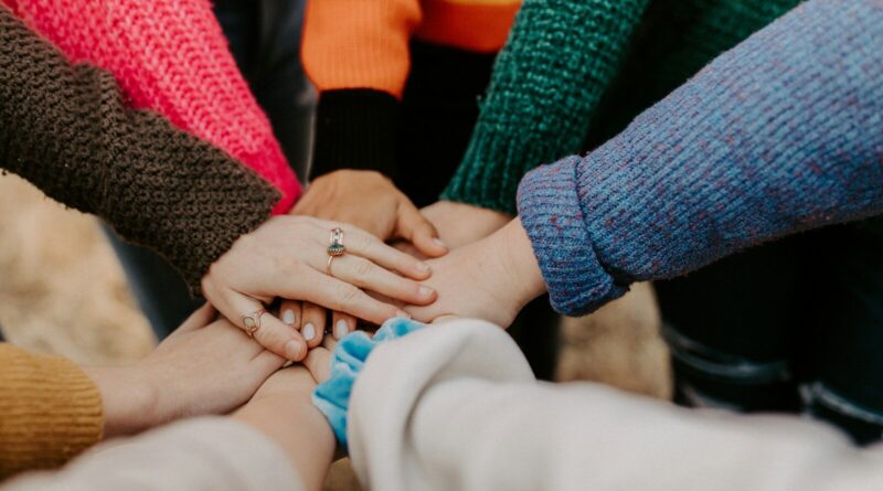 person in red sweater holding babys hand