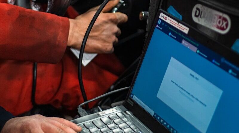 A man sitting in a car using a laptop computer